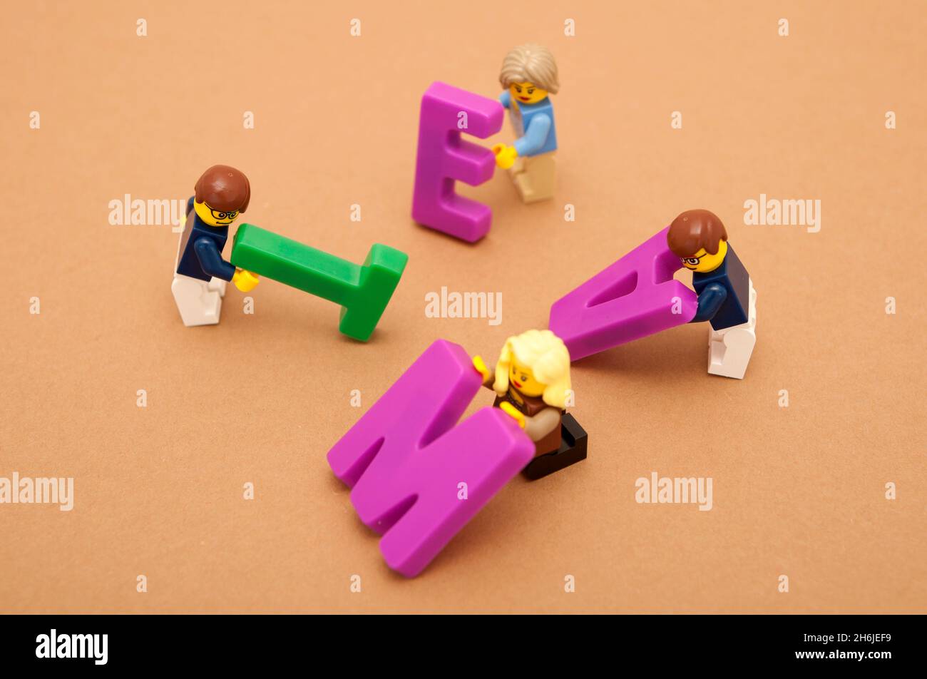 A group of small toy men and women building the word 'team' from large letters Stock Photo