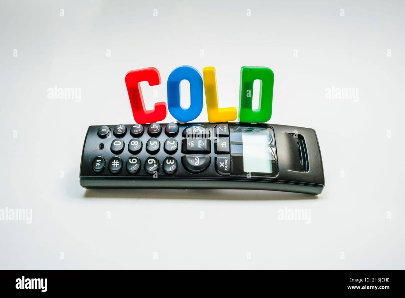 plastic letters spelling out COLD on top of a phone, symbolising cold calling marketing technique. Stock Photo