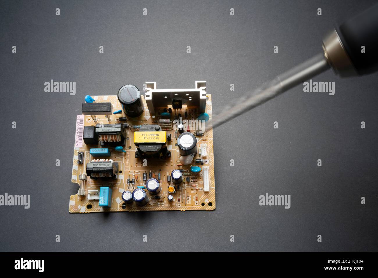 Drill hovering over electric component circuit board suggesting botched repairs or sabotage or hacking Stock Photo