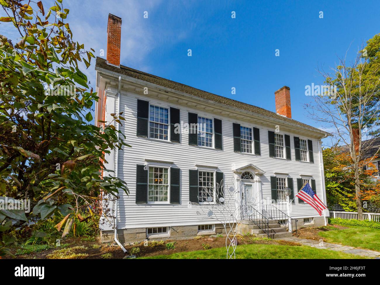 Typical local style white clapboard faced house with patriotic American flag in Woodstock, Vermont, New England, USA Stock Photo