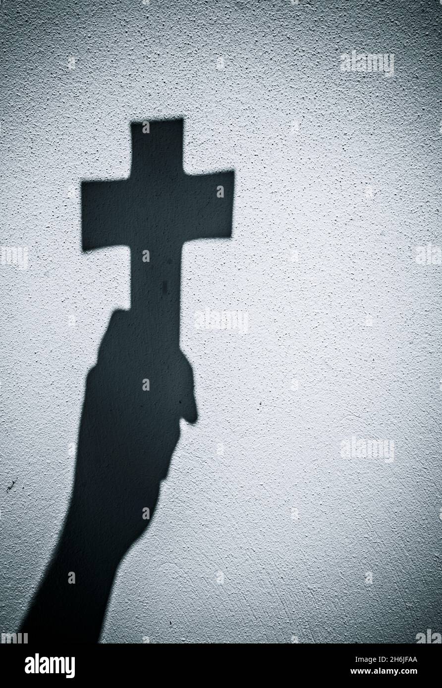 Silhouette of hand holding up crucifix Stock Photo