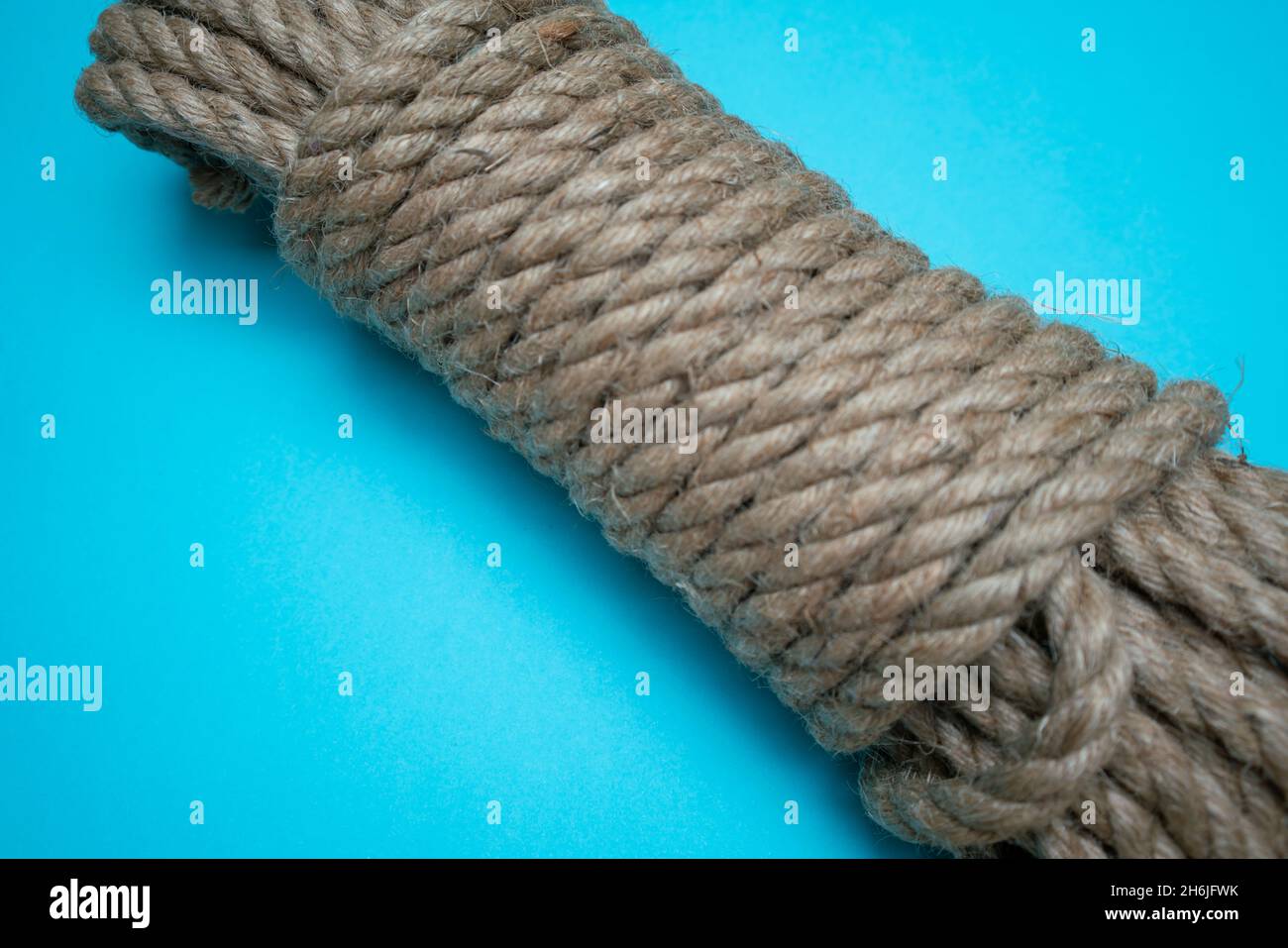 a fresh coil of new rope against a blue background Stock Photo
