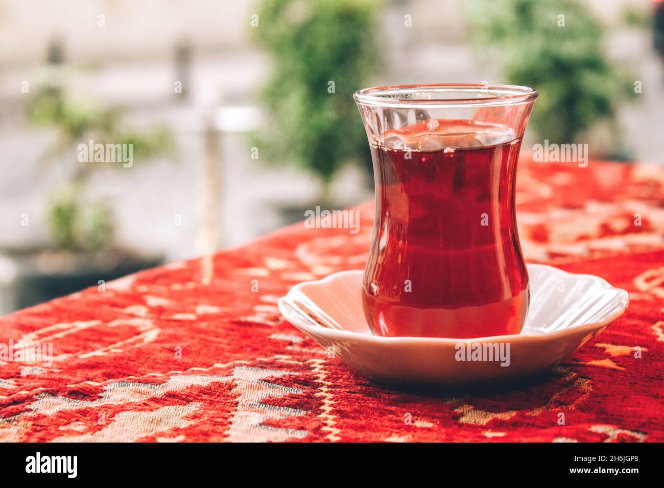 Traditional Turkish tea in special tulipshaped glass on red tablecloth