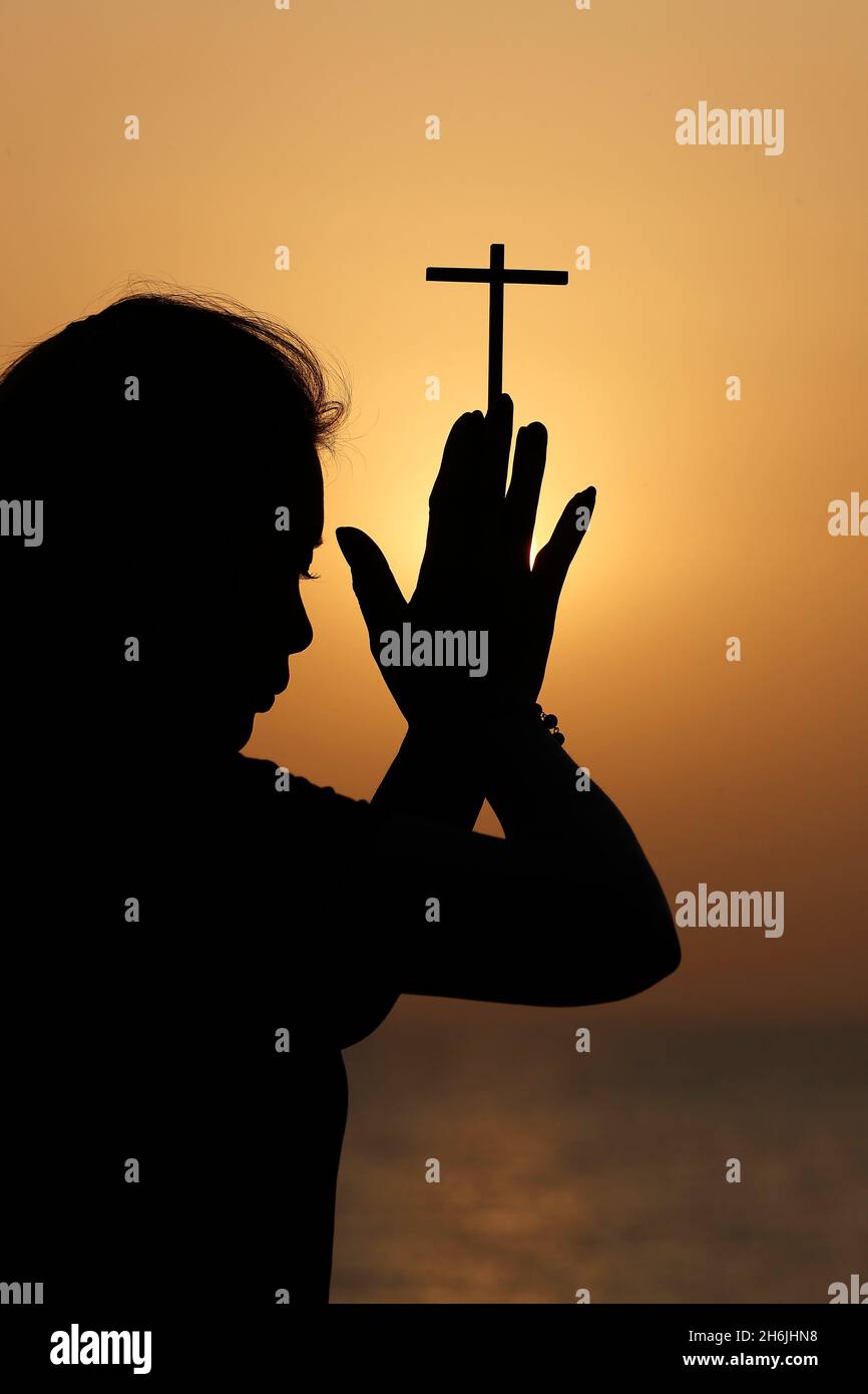 Silhouette of faithful religious woman praying with Christian cross at  sunset, United Arab Emirates, Middle East Stock Photo - Alamy, image size:866x1390