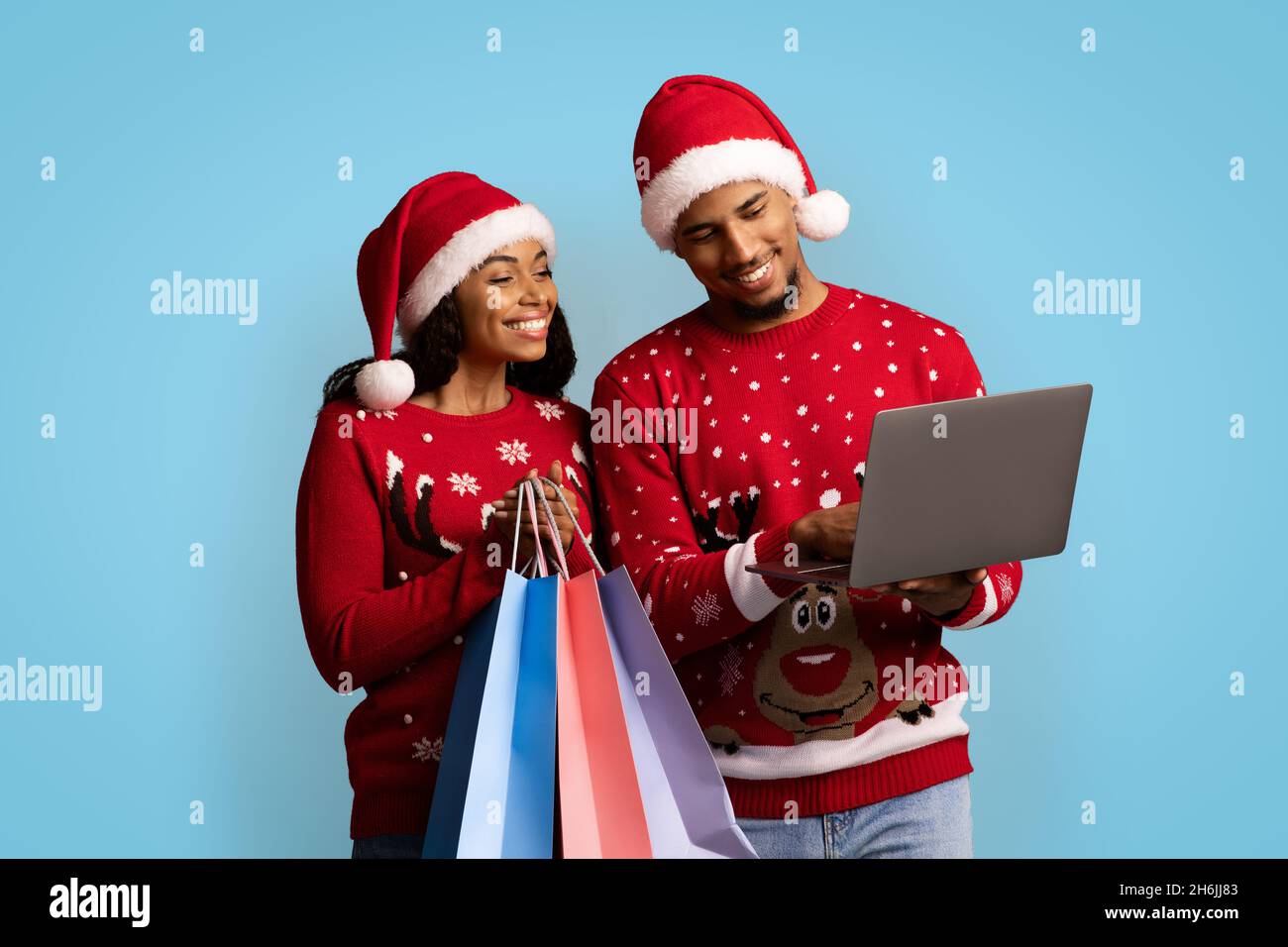 Smiling black shopaholics enjoying Christmas sales, using laptop Stock Photo