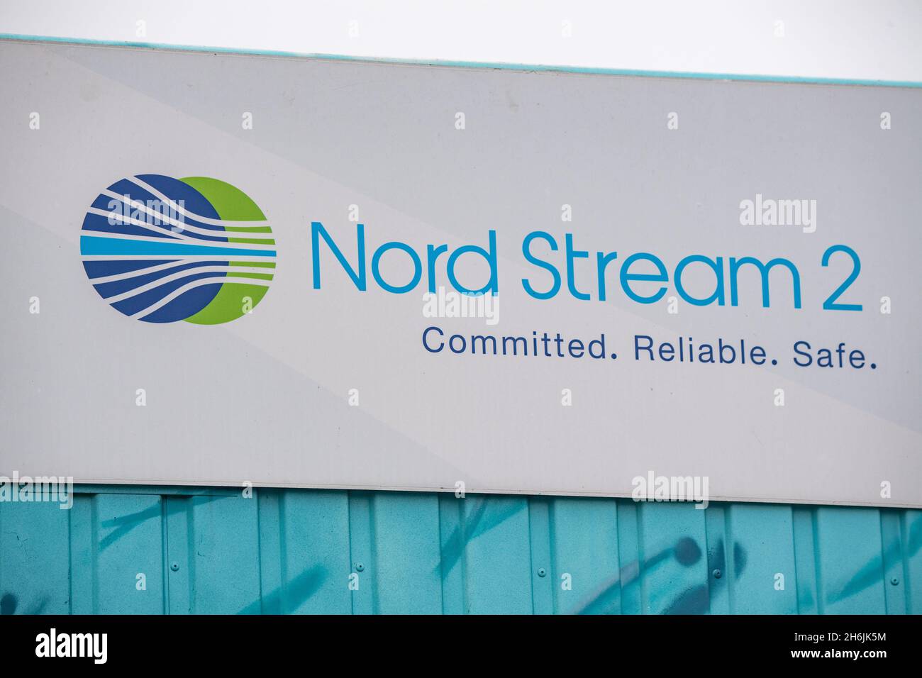 Lubmin, Germany. 16th Nov, 2021. A sign reading 'Nord Stream 2 Committed Reliable Safe' hangs above a painted map at the natural gas receiving station in the Lubmin industrial estate. The Higher Administrative Court (OVG) of Mecklenburg-Western Pomerania is hearing a lawsuit filed by Deutsche Umwelthilfe (DUH) against Nord Stream 2. DUH had sued in the summer of 2020 for a review of the construction and operating permit for Nord Stream 2 by the Stralsund Mining Authority. Credit: Stefan Sauer/dpa/Alamy Live News Stock Photo