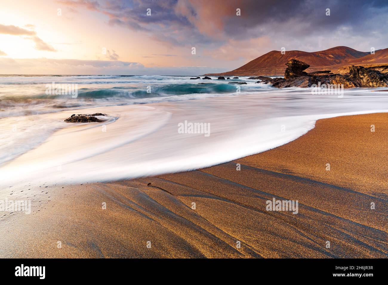 Foam of sea waves on golden sand beach at sunset, Playa de la Solapa, Pajara, Fuerteventura, Canary Islands, Spain, Atlantic, Europe Stock Photo