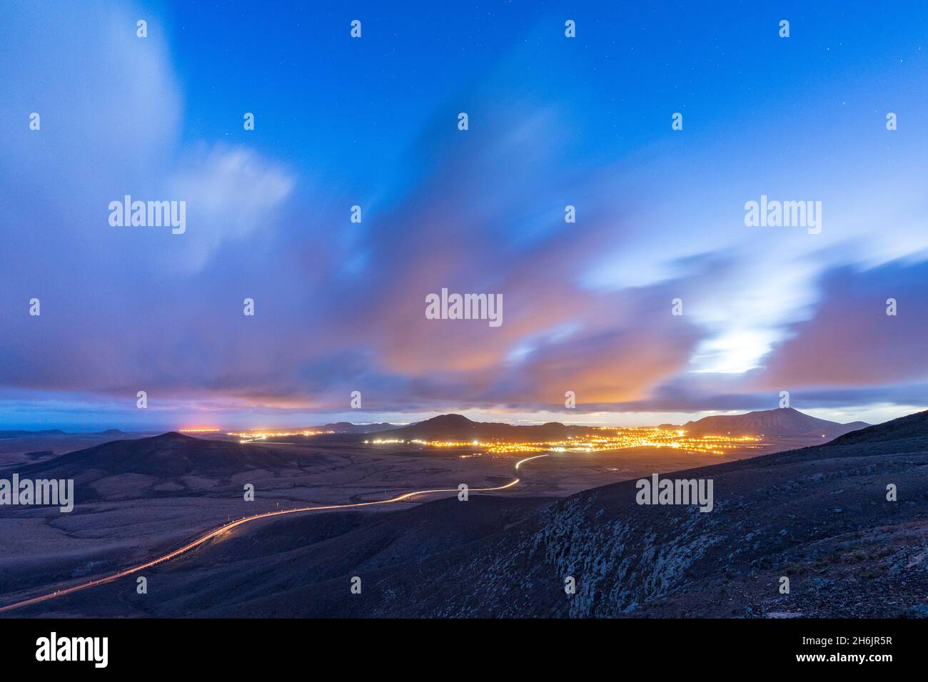 Car trail lights on desert road crossing the barren land at dusk, Vallebron lookout, Fuerteventura, Canary Islands, Spain, Atlantic, Europe Stock Photo