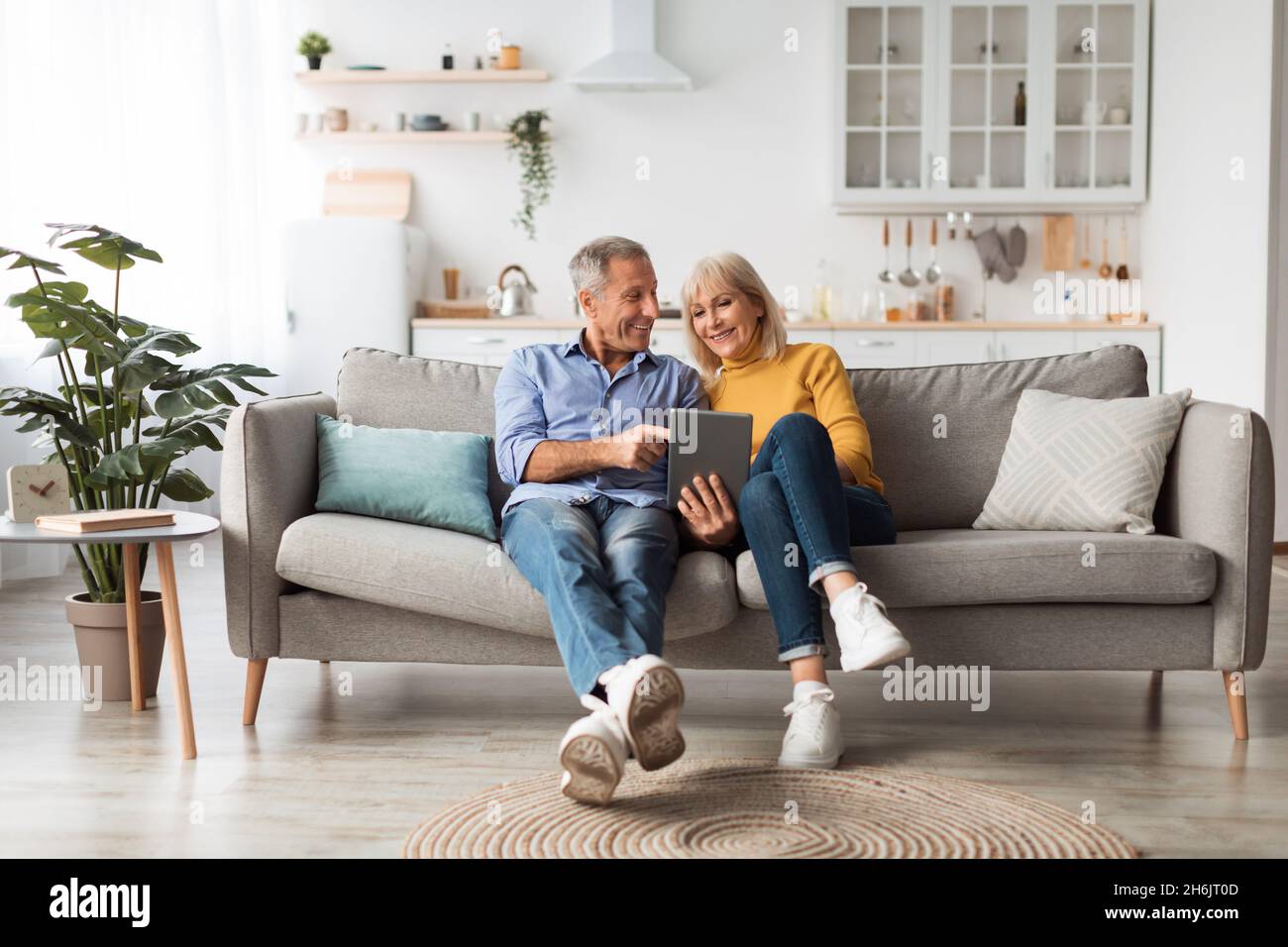 Cheerful Mature Spouses Using Digital Tablet At Home Stock Photo