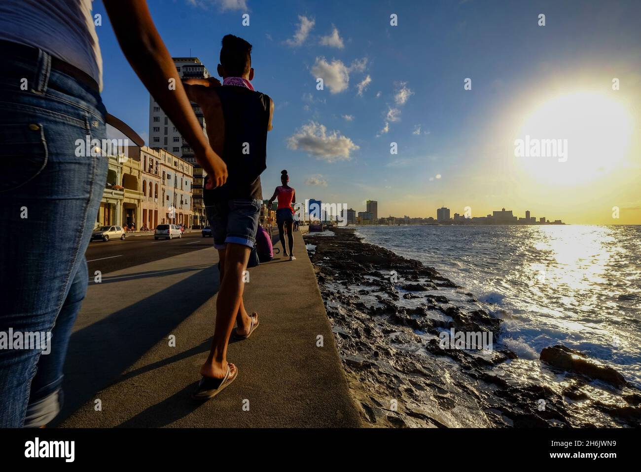 People walk along the Malecon as the sun sets, Havana, Cuba, West Indies, Central America Stock Photo