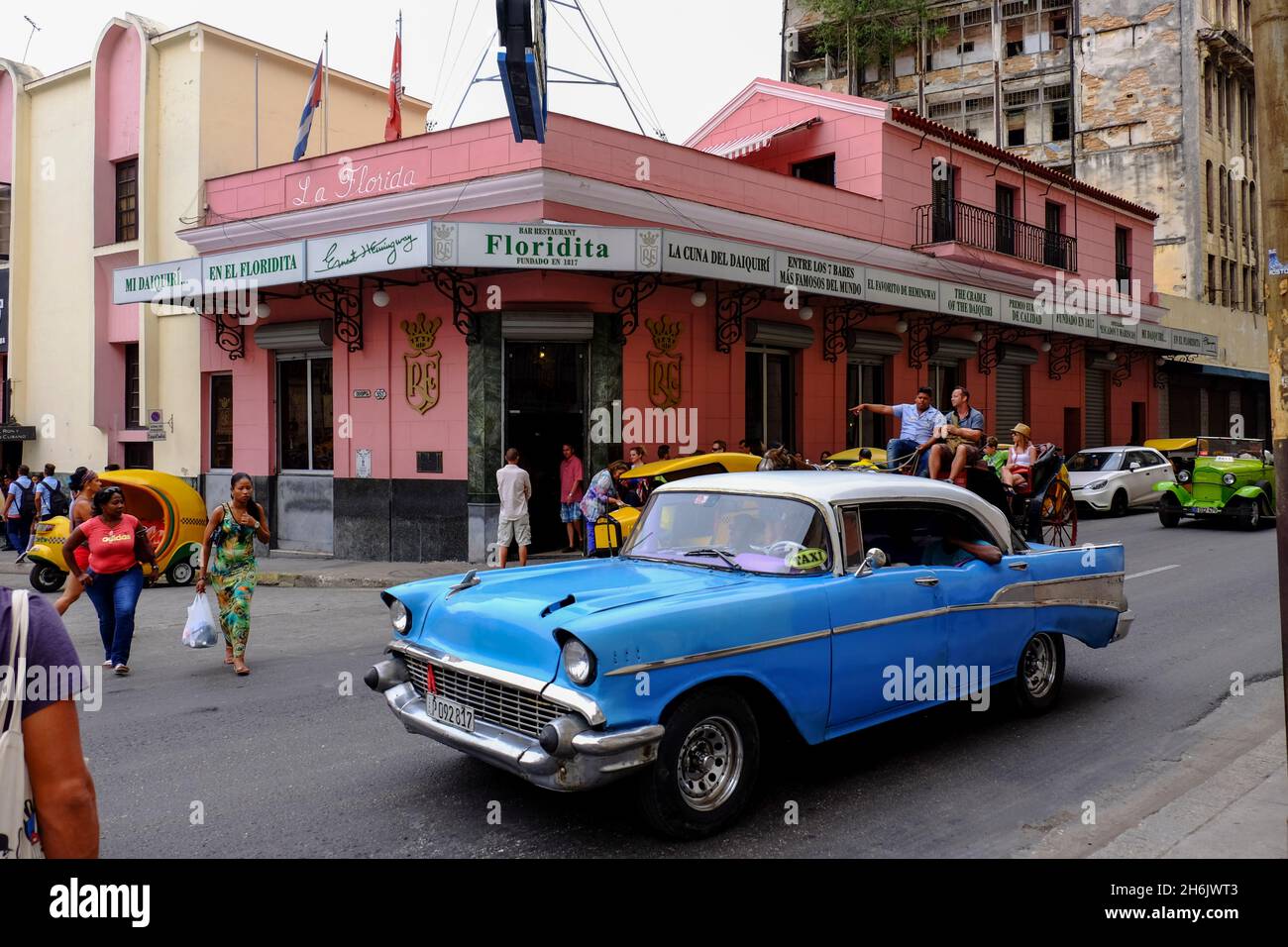 Pedestrians, vintage cars, and a horse-drawn carriage travel past Floridita on the streets of Havana, Havana, Cuba, West Indies, Central America Stock Photo
