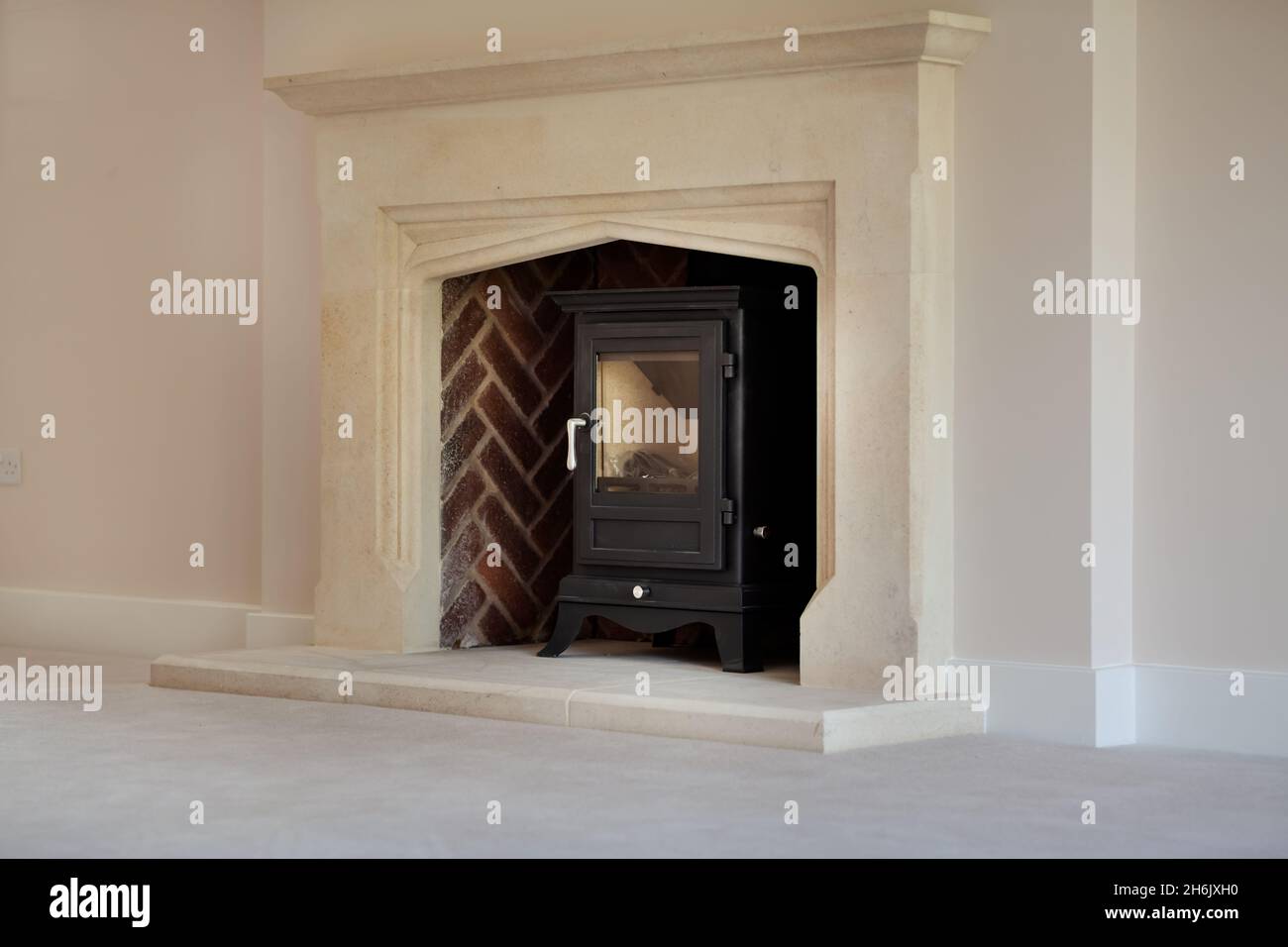 Clavering, England -  April 6 2020: New Home cast iron wood burning stove with stone surround, mantelpiece and hearth Stock Photo