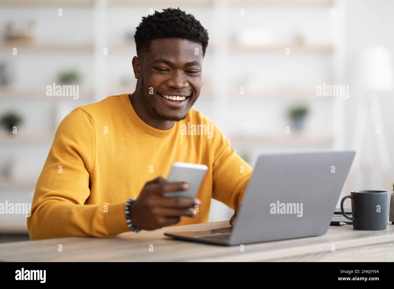 Young black man entrepreneur working on laptop and using cellphone Stock Photo