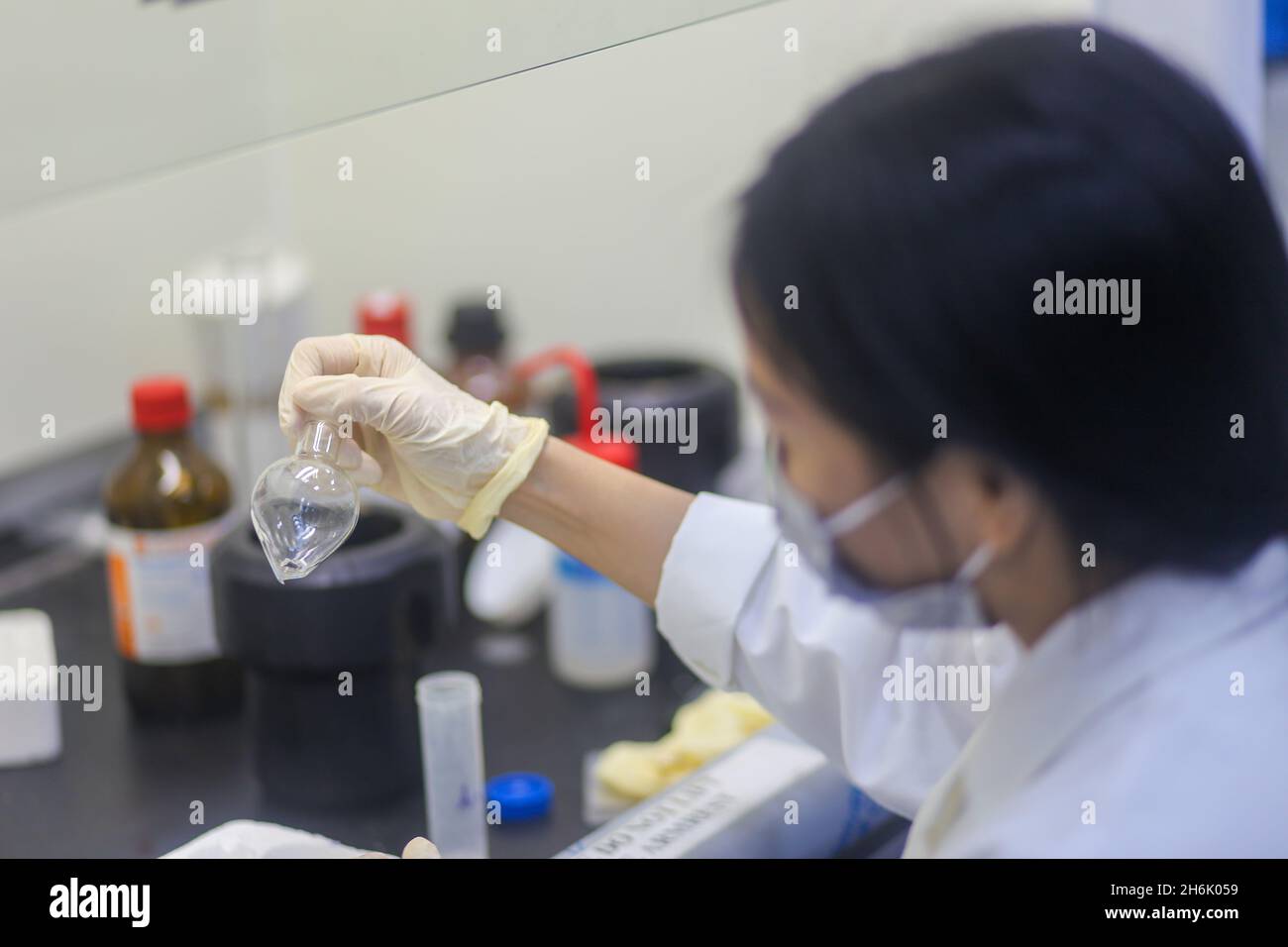 Closeup of an Asian woman scientist checking glass flask of an experiment in the laboratory Stock Photo