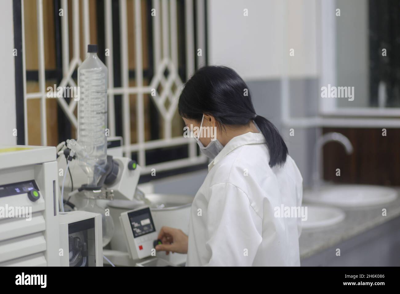 Vietnamese woman scientist operating a rotary evaporator to make an experiment in the laboratory Stock Photo