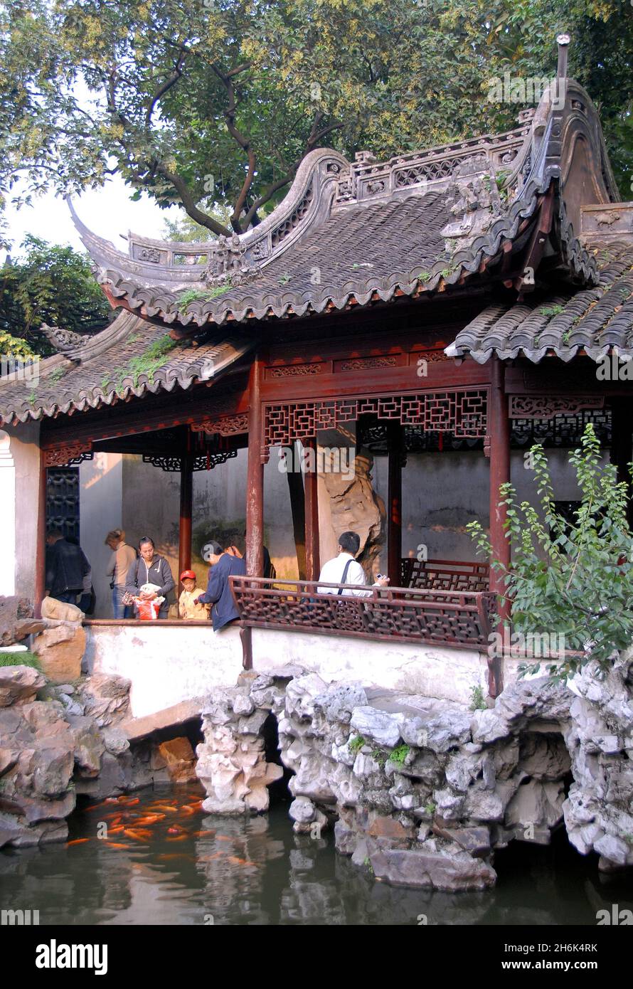 Yu Yuan Gardens, Shanghai, China: People in the Yu Garden looking at the fish in a small pond. Yu Yuan is a traditional Chinese garden. Stock Photo