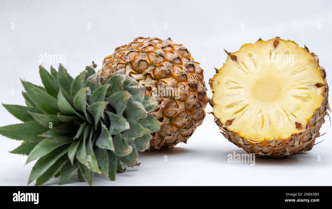 Fresh pineapple with slices on outdoor table, ananas on green garden background Stock Photo