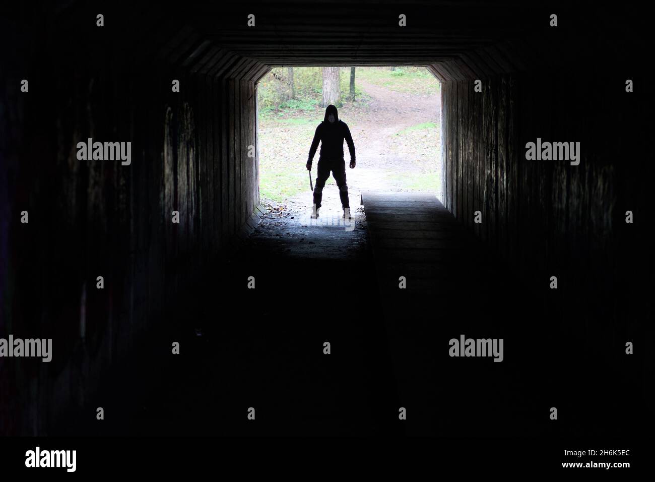 Serial killer Jason Voorhees in hockey mask and machete in the end of the dark tunnel. Friday 13h cosplay costume.  Stock Photo