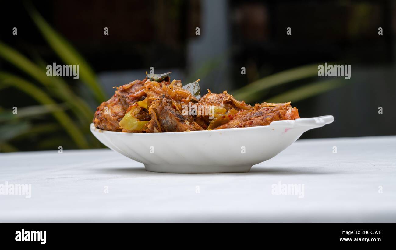 Spiced devilled Chicken on white surface with green nature outdoor background. Stock Photo