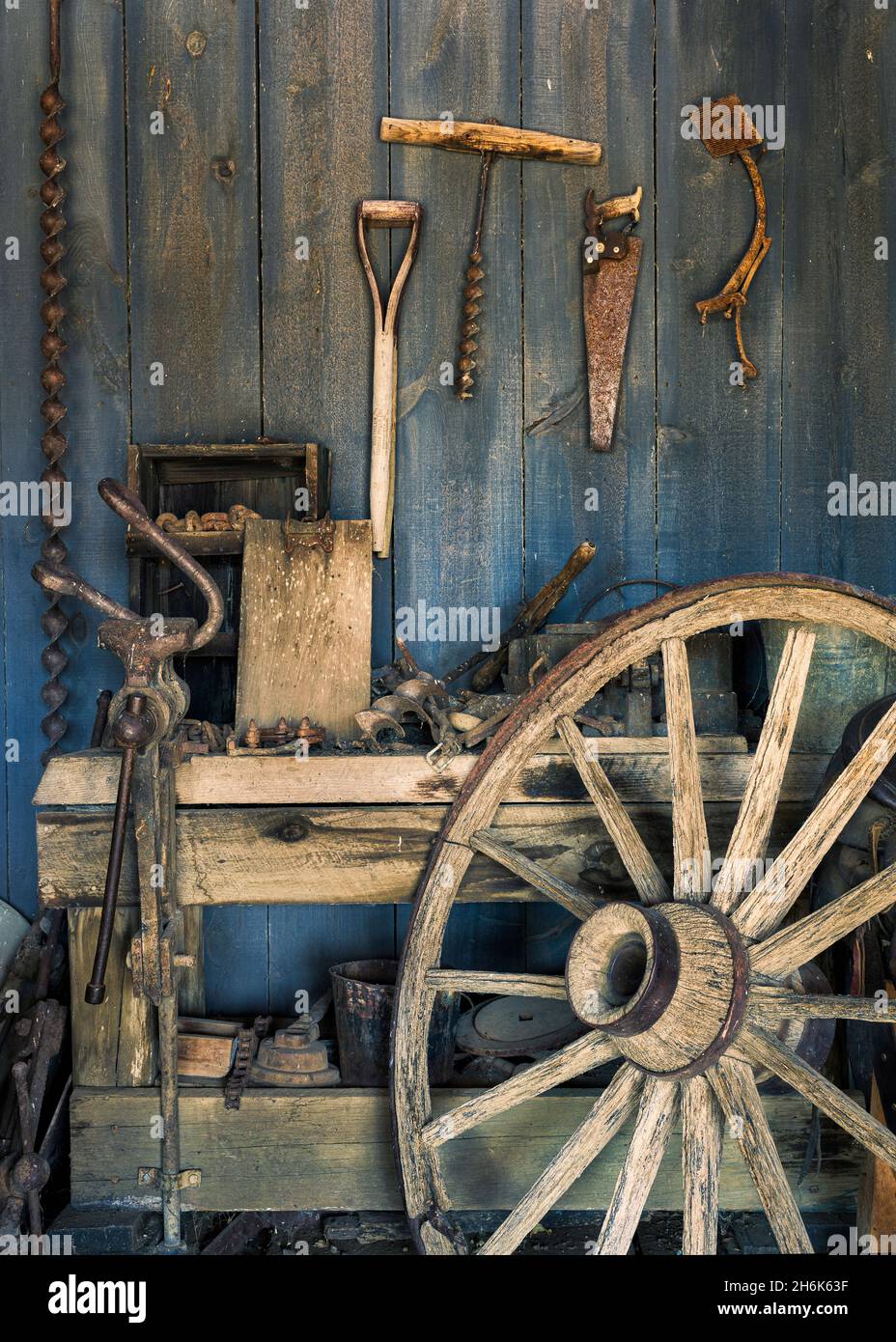 Old wooden wagon wheel against work bench in blacksmith repair shop Stock Photo