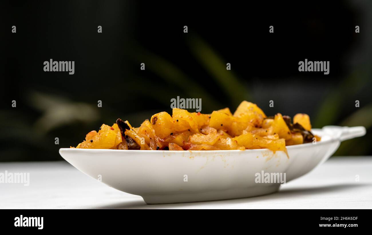 Pineapple chutney in white plate/bowl on a table with green outdoor background. Stock Photo