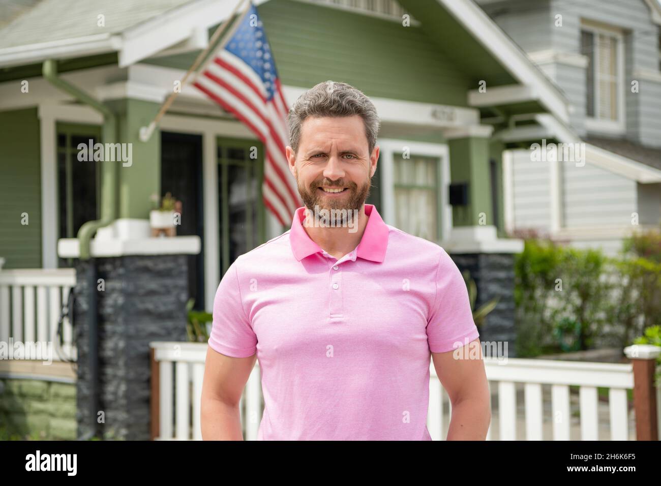 happy bearded man realtor selling or renting house with american flag, real estate Stock Photo