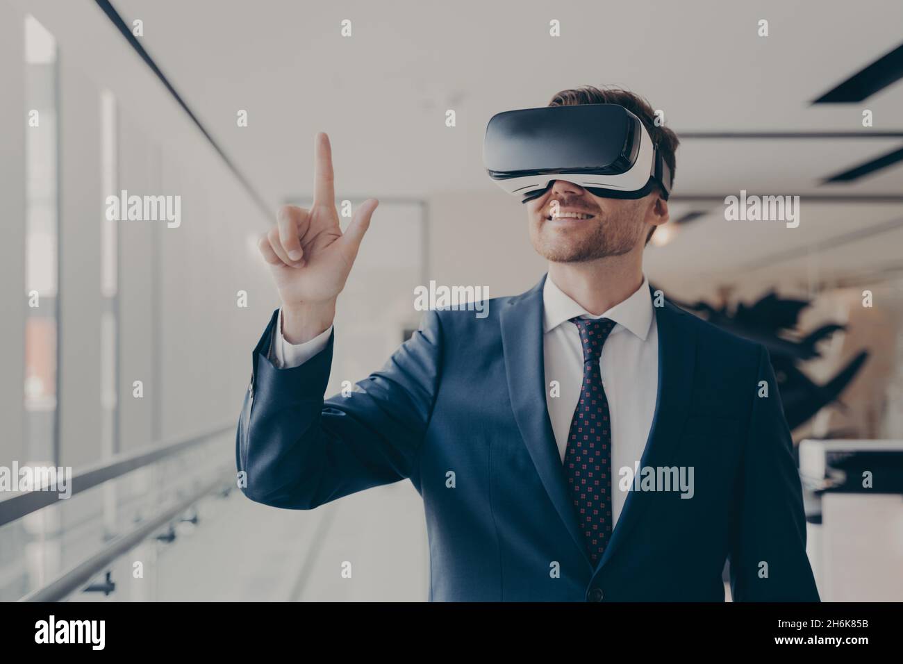 Cheerful businessman dressed formally using vr headset at work Stock Photo