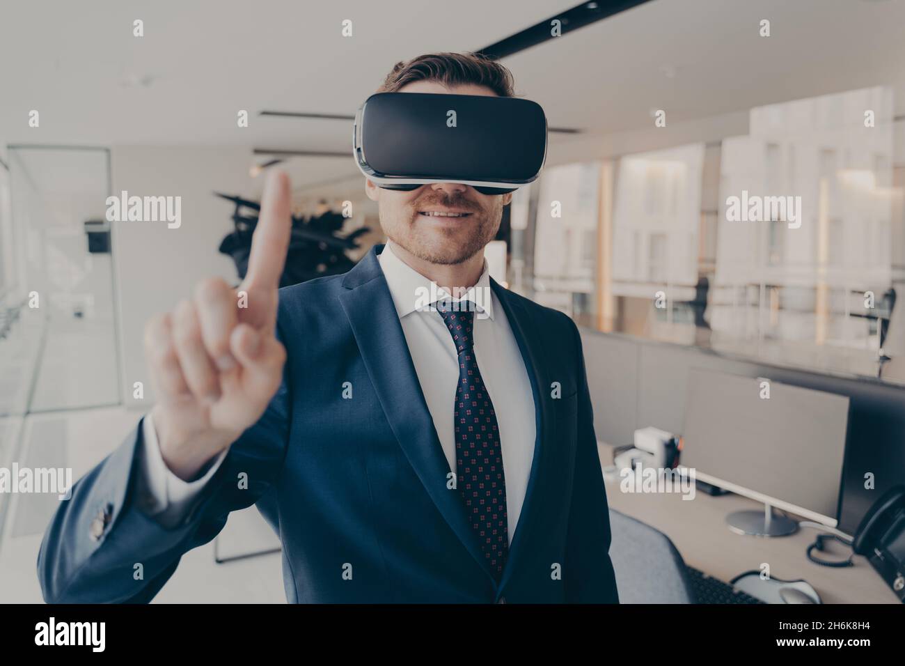 CEO man stands in office with VR headset and interacts with application virtual interface Stock Photo