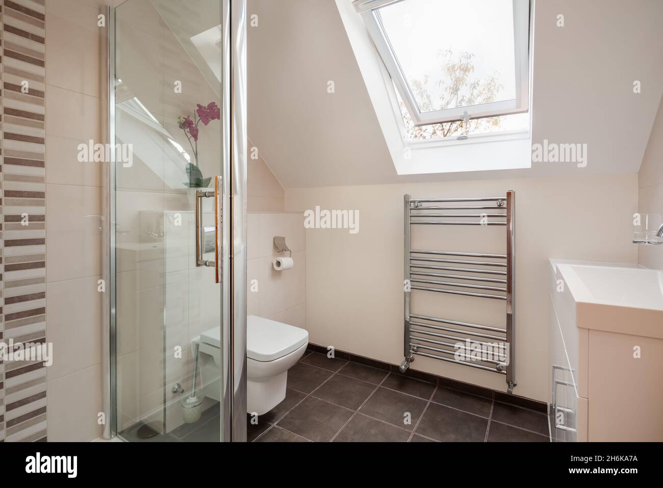 Essex, England - November 18 2019: Contemporary modern tiled bathroom shower room with ceramic sink, towel rail and toilet wc Stock Photo
