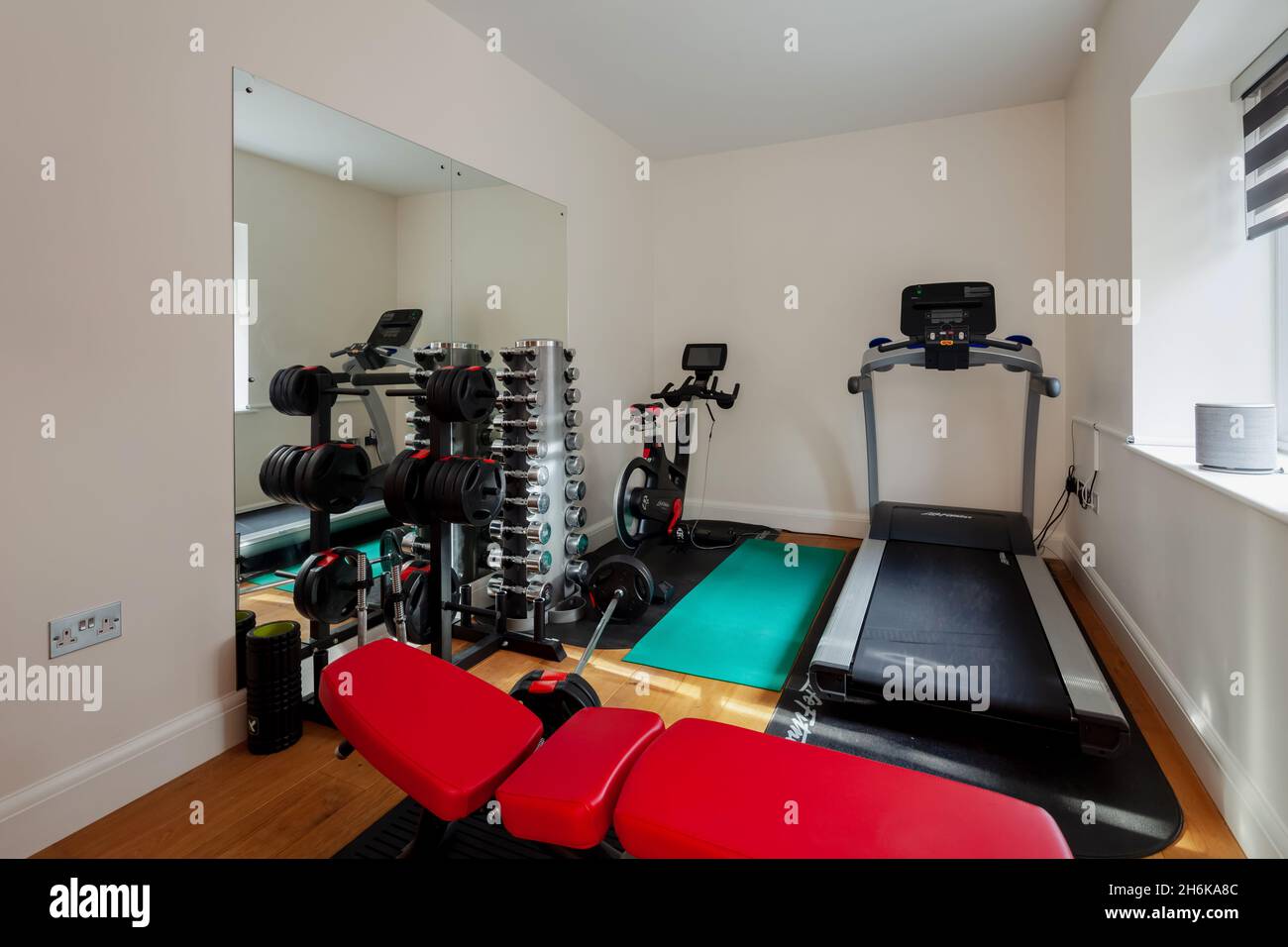 Essex, England - November 18 2019: Indoor domestic residential gymnasium inside home with weights, running machine, exercise bike and bench. Stock Photo