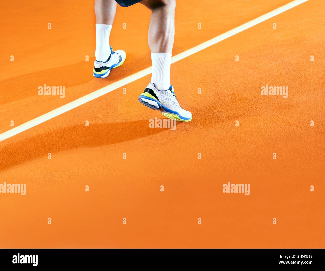 Male tennis player in action on orange court Stock Photo