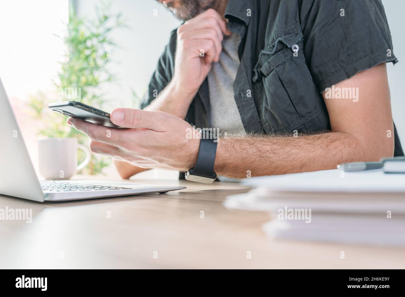 Freelancer using mobile smart phone in home office, selective focus Stock Photo