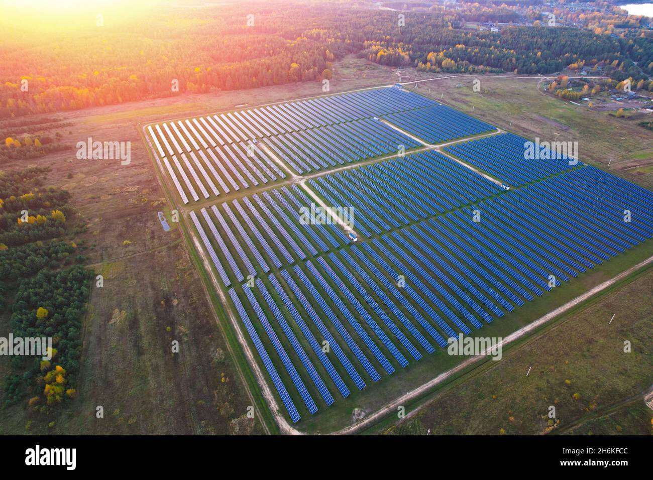 Solar power plant panels in the field with the glare of the evening sun in solar cells. Stock Photo