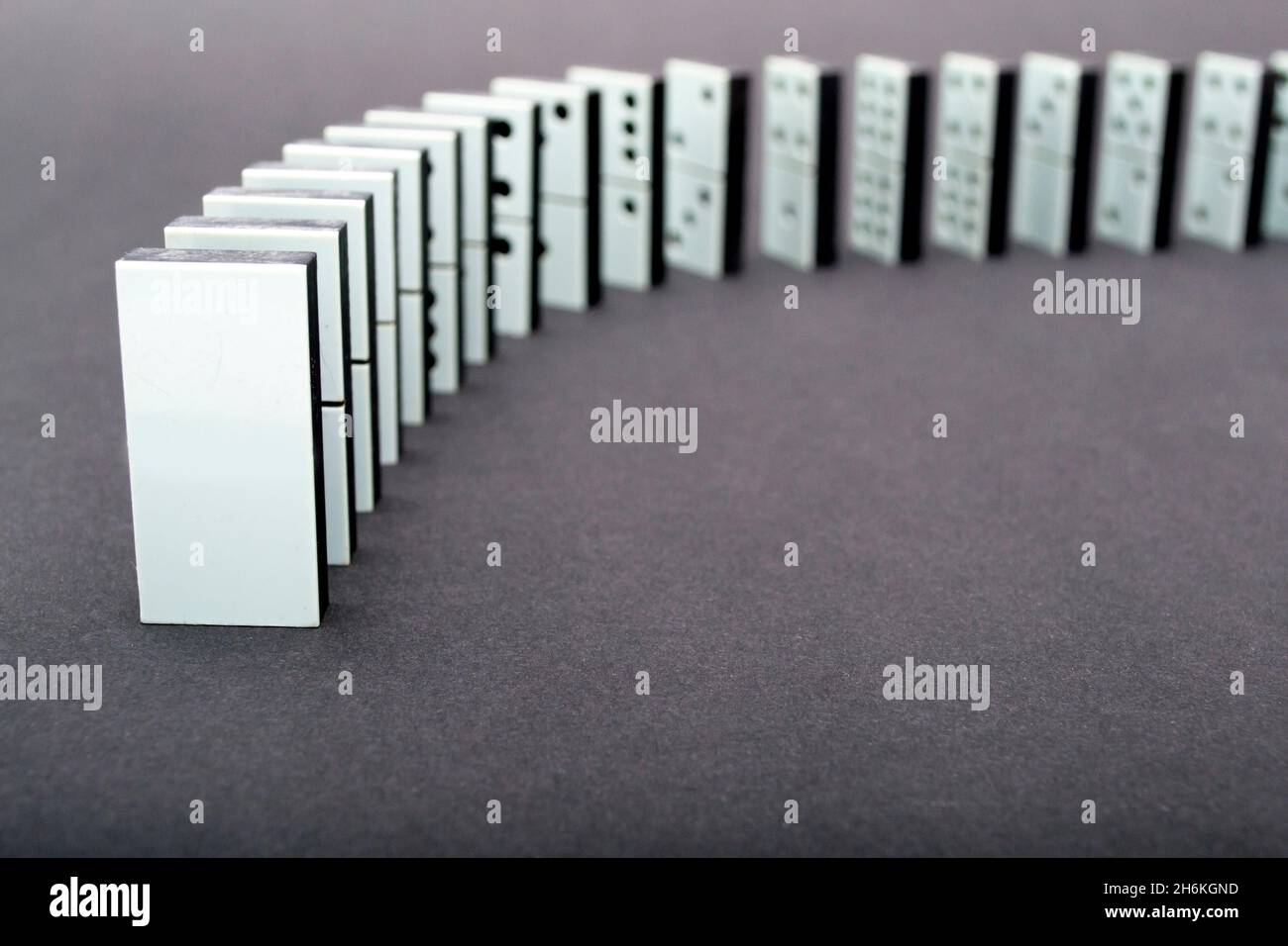 Dominoes falling in a row , gray background Stock Photo - Alamy