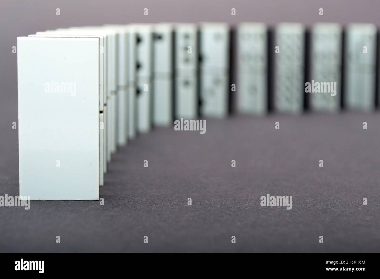 Dominoes falling in a row , gray background Stock Photo - Alamy