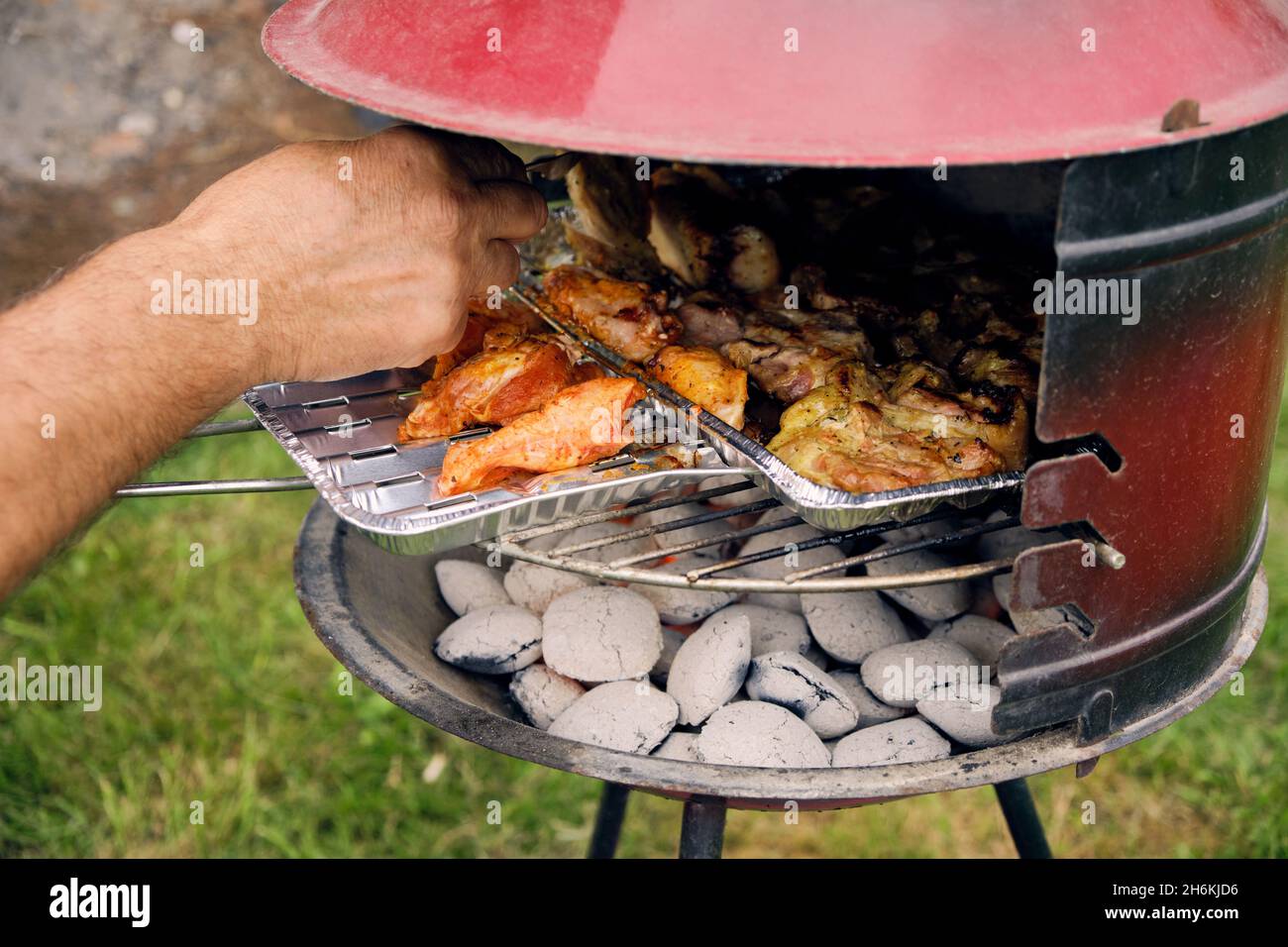 close-up of an elderly man's hand turning meat on the grill Stock Photo
