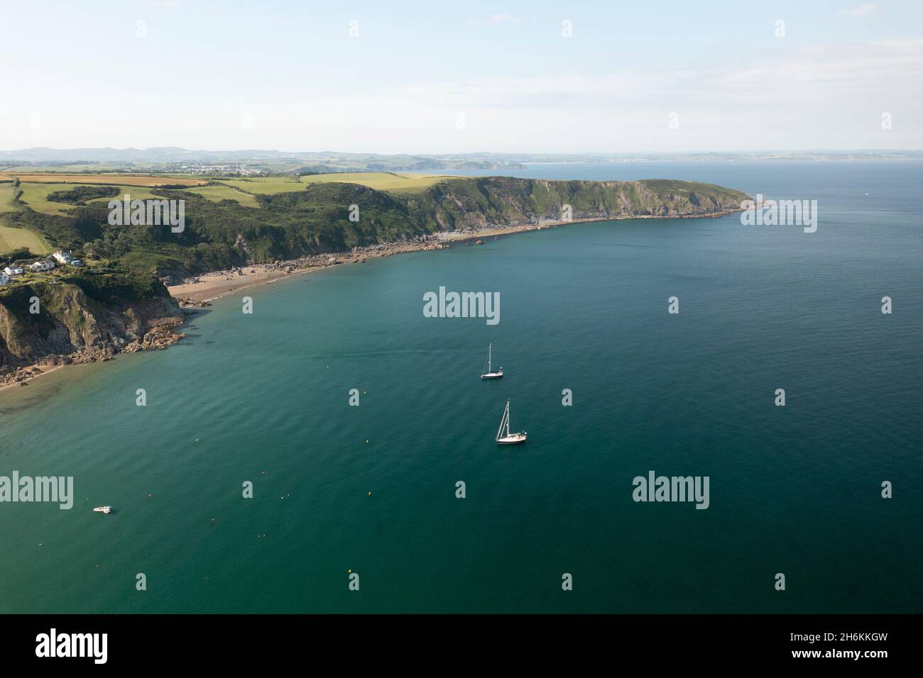The Cornish coastline from Gorran Haven showing yachts in the calm sea Stock Photo