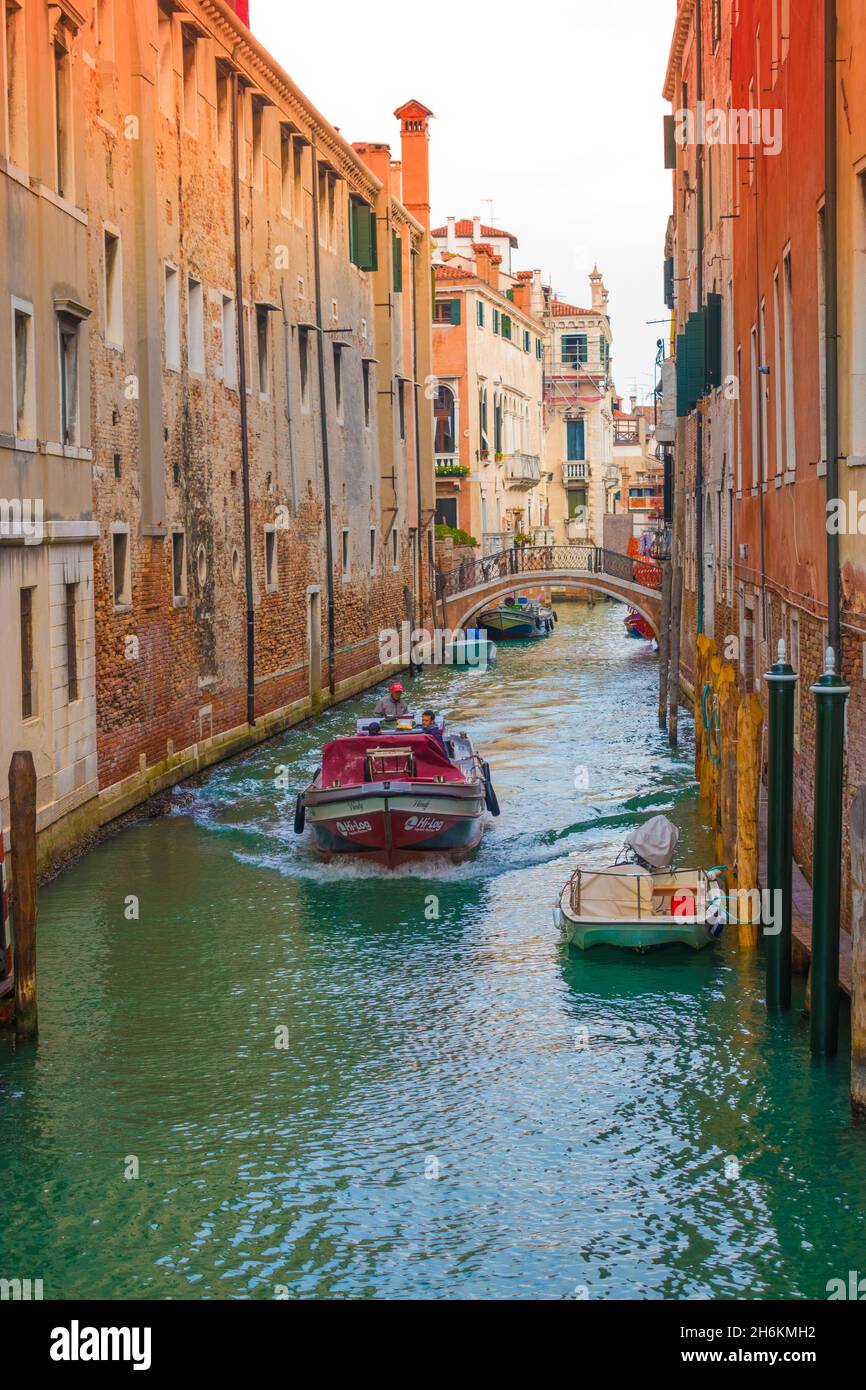 Work boat heading on narrow canal  lined with old tall buildings Rio de La Pleta Venice Italy Stock Photo