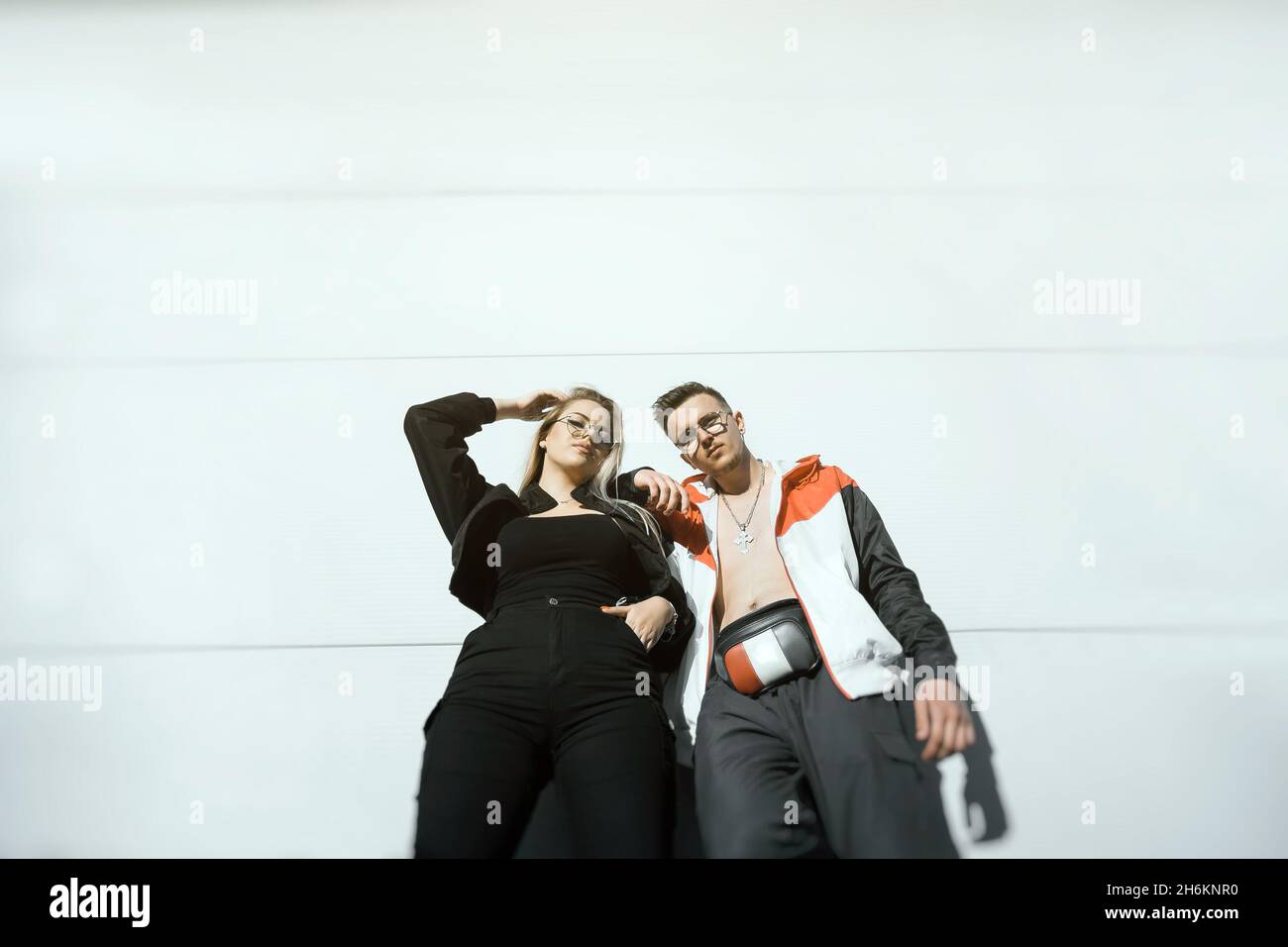 Two young people posing on a white wall, modern urban couple concept Stock Photo