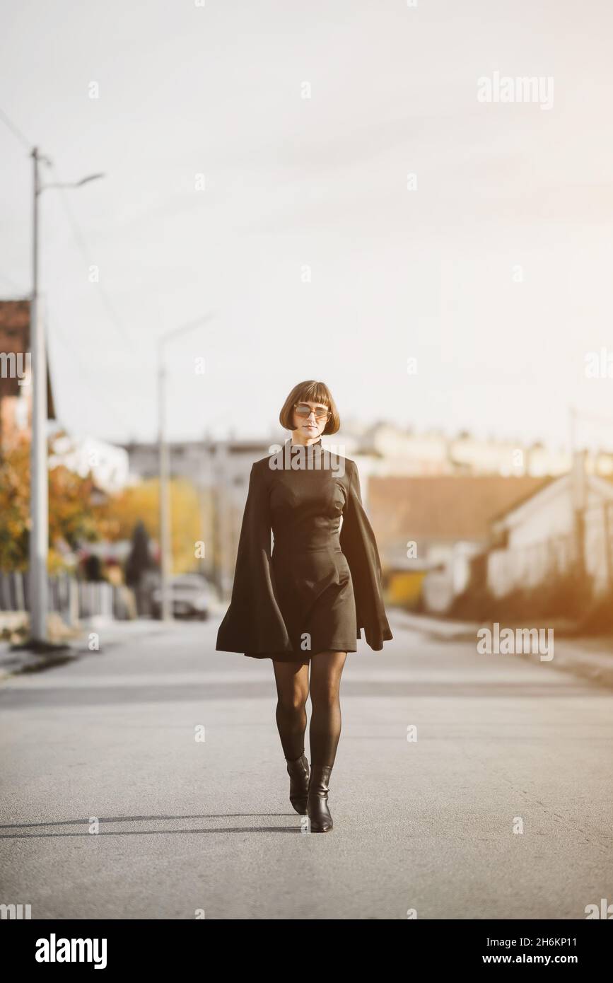 Fashionable young woman in black dress walks down the street, fashion and clothing concept Stock Photo