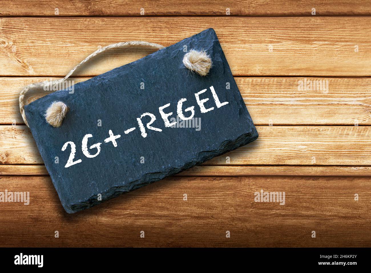 German Corona 2G+ Rule and sign on wooden background Stock Photo