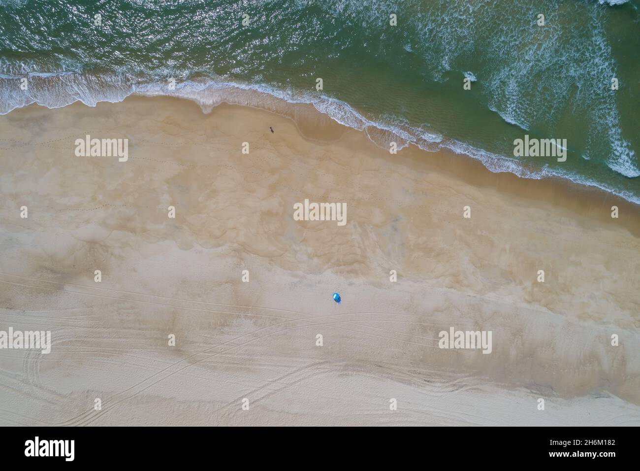 Aerial view of the wavy sea hitting the sandy beach on the coast Stock