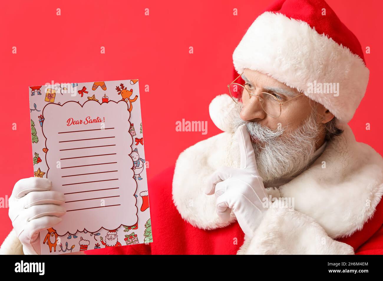 Santa Claus with letter showing silence gesture on color background Stock Photo