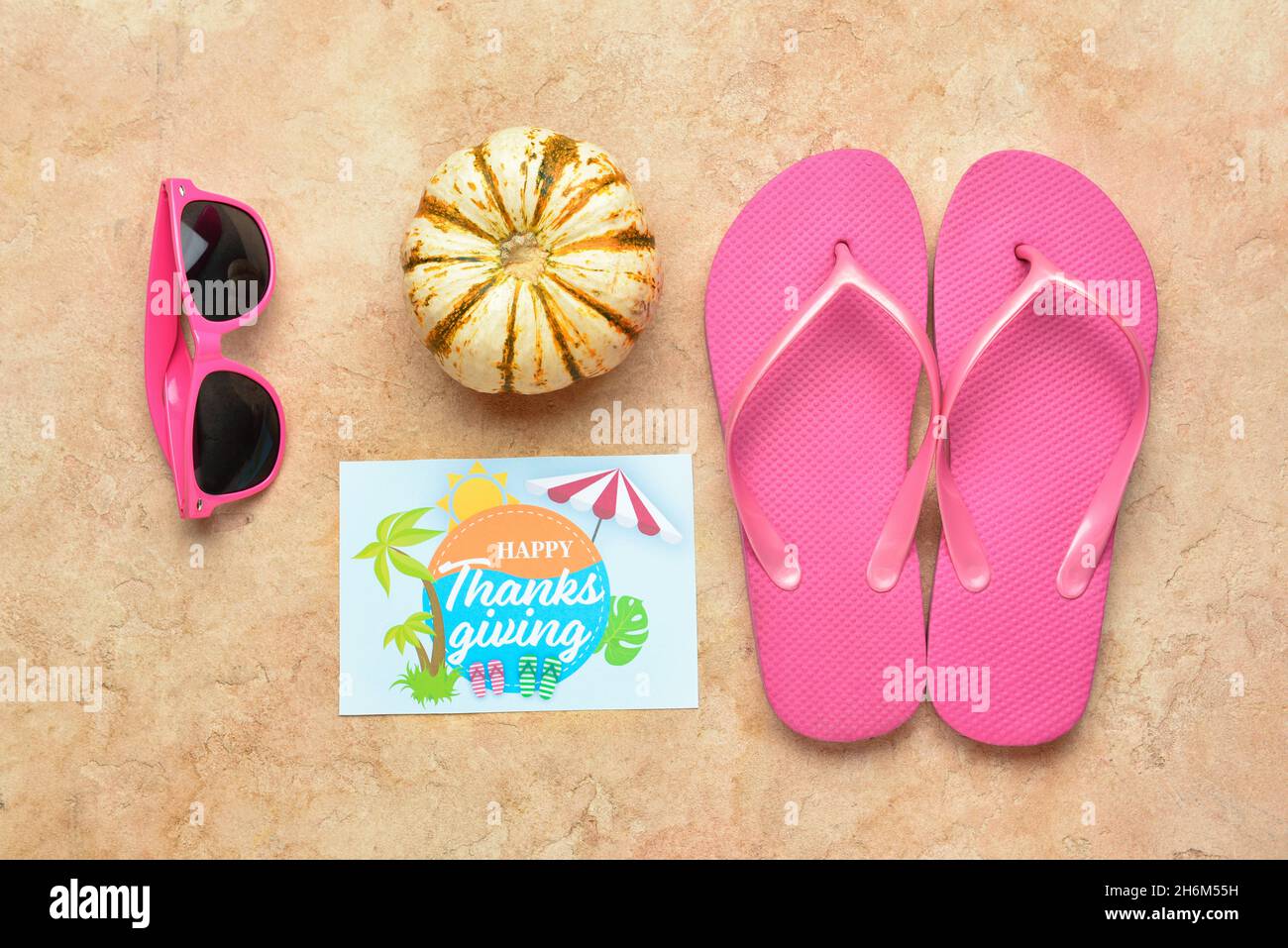 Sunglasses, pumpkin, flip flops and paper card with text HAPPY THANKSGIVING  on color background Stock Photo - Alamy