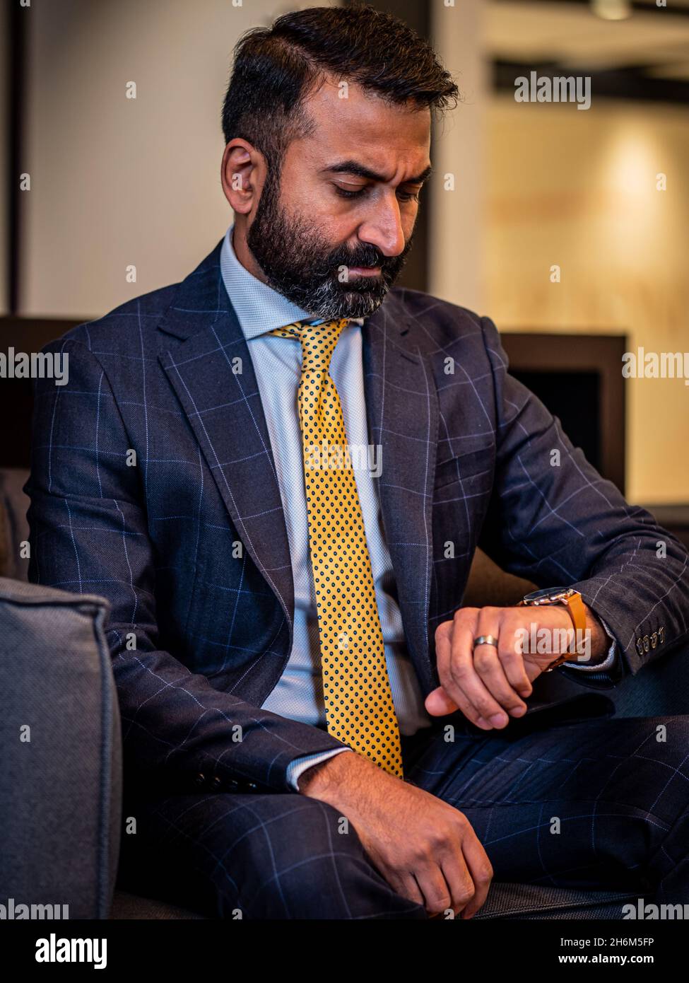 Vertical shot of a businessman in a blue suit and yellow tie checking his  watch in Canada Stock Photo - Alamy