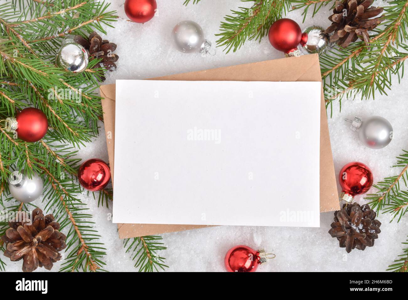 https://c8.alamy.com/comp/2H6M6BD/one-empty-card-is-lying-on-a-kraft-envelope-in-the-snow-with-a-christmas-tree-and-glass-balls-banner-invitation-postcard-flatlay-flatlay-flatlay-2H6M6BD.jpg