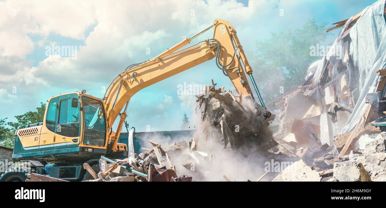 Excavator breaking house. Old building demolishing panoramic image Stock Photo