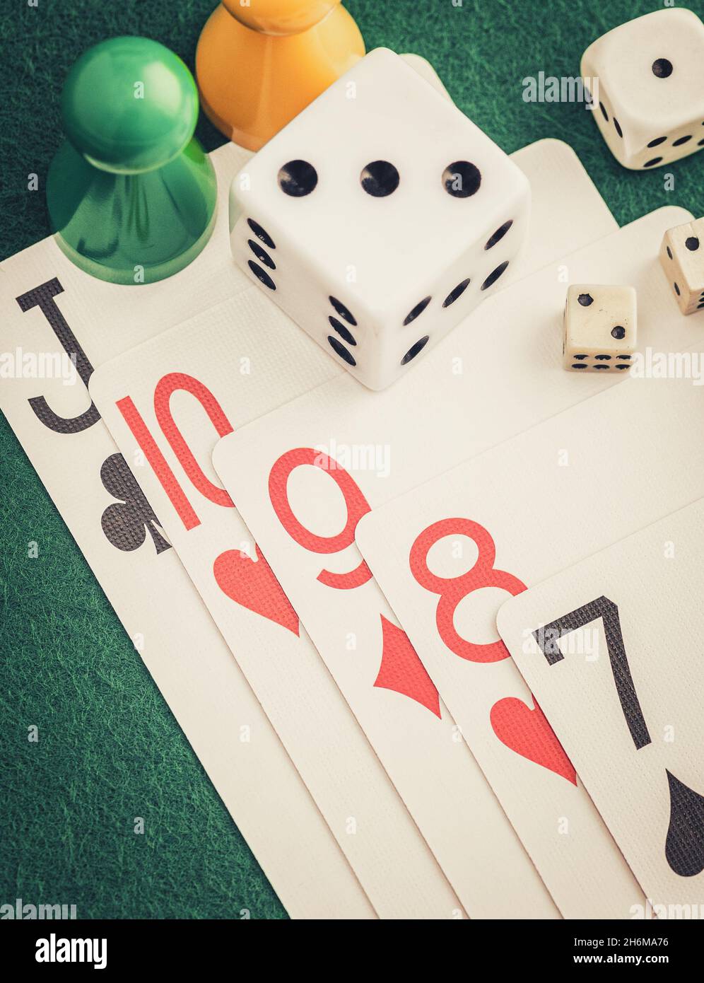 Playing cards and board game figures arranged on a poker table in a