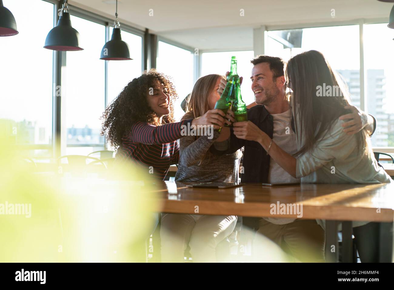 Smiling colleagues toasting drink bottles in office Stock Photo