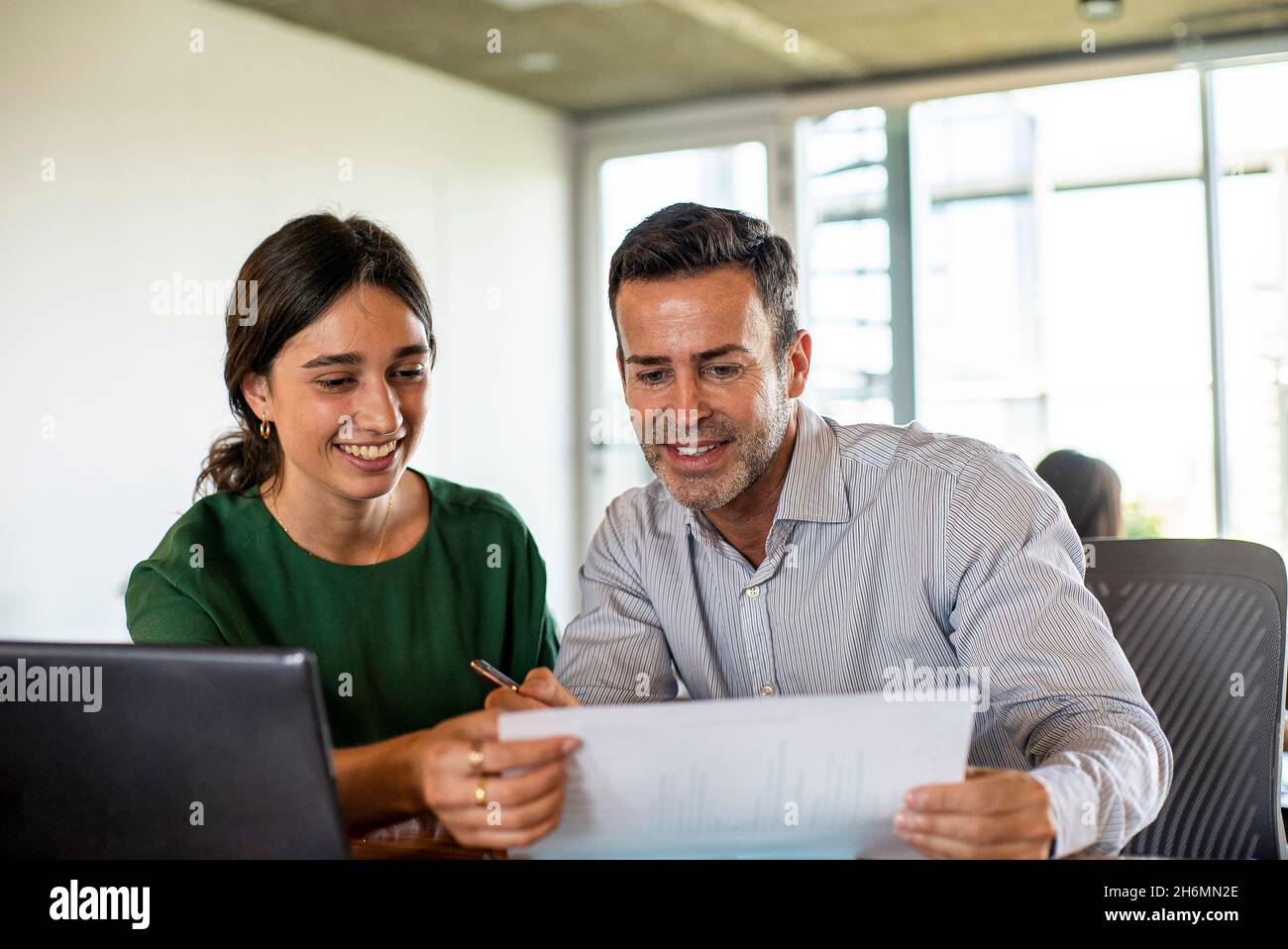 Smiling young woman and mature man working in office Stock Photo